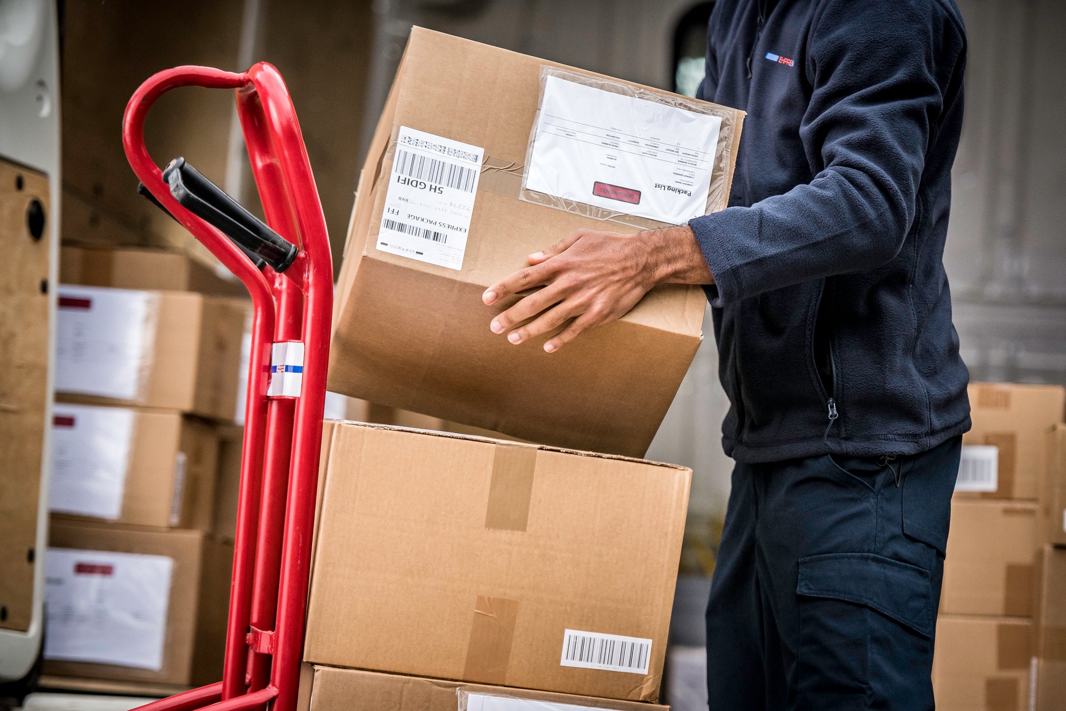 delivery-man-picking-parcel-from-trolley