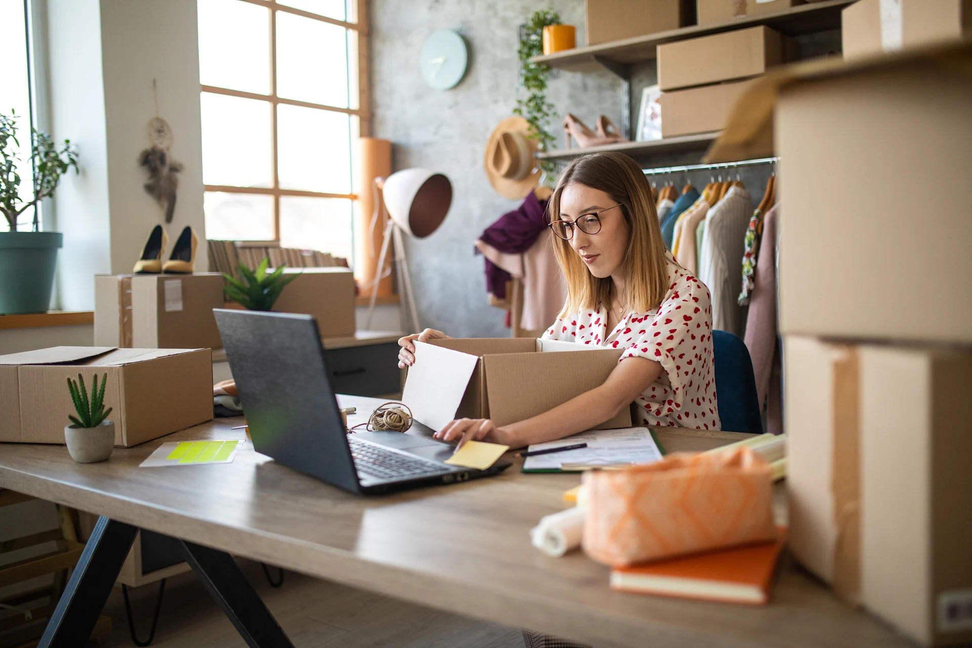 Woman booking parcel delivery on laptop while packaging