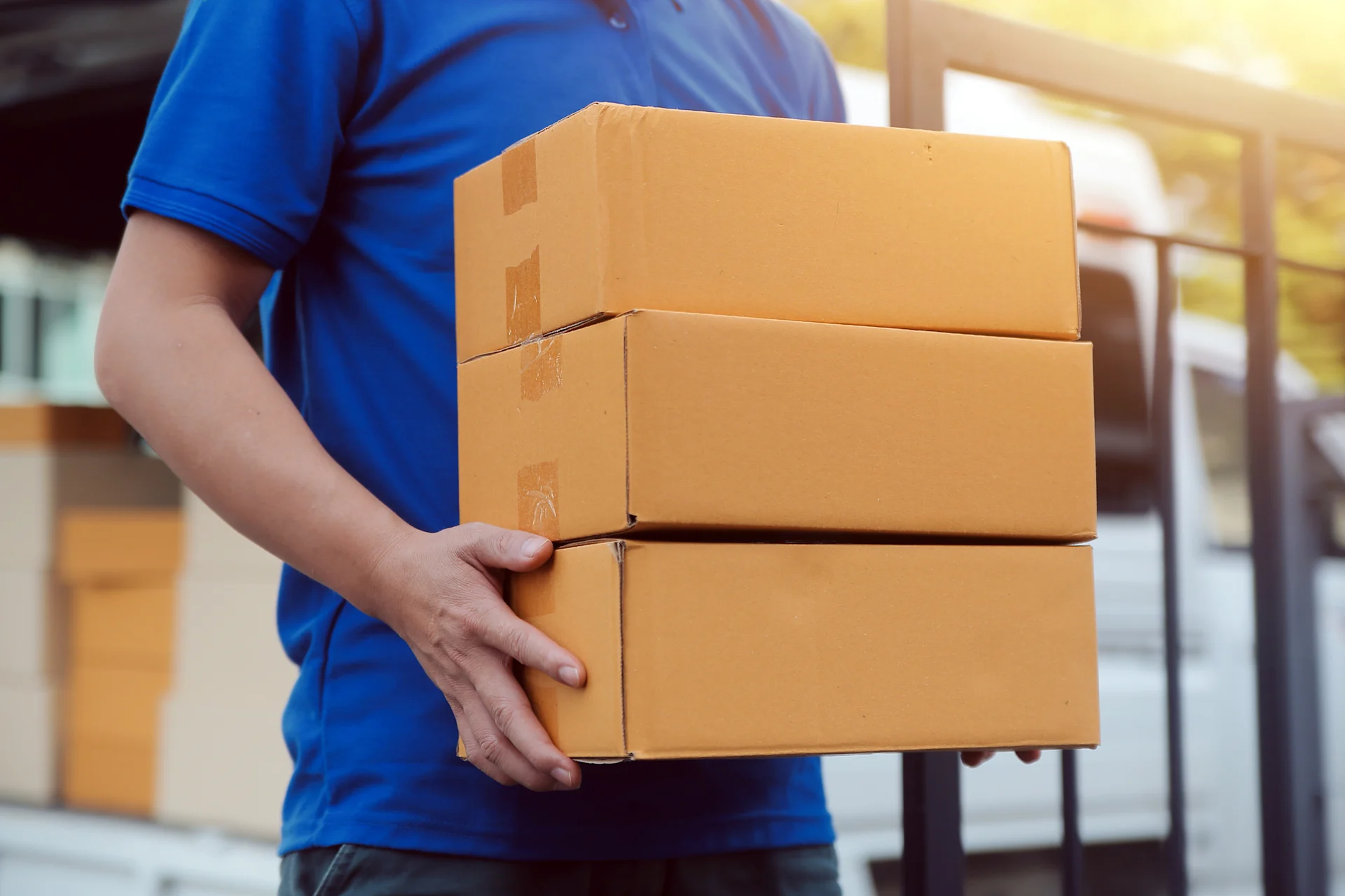 Courier in blue shirt carrying stack of parcels