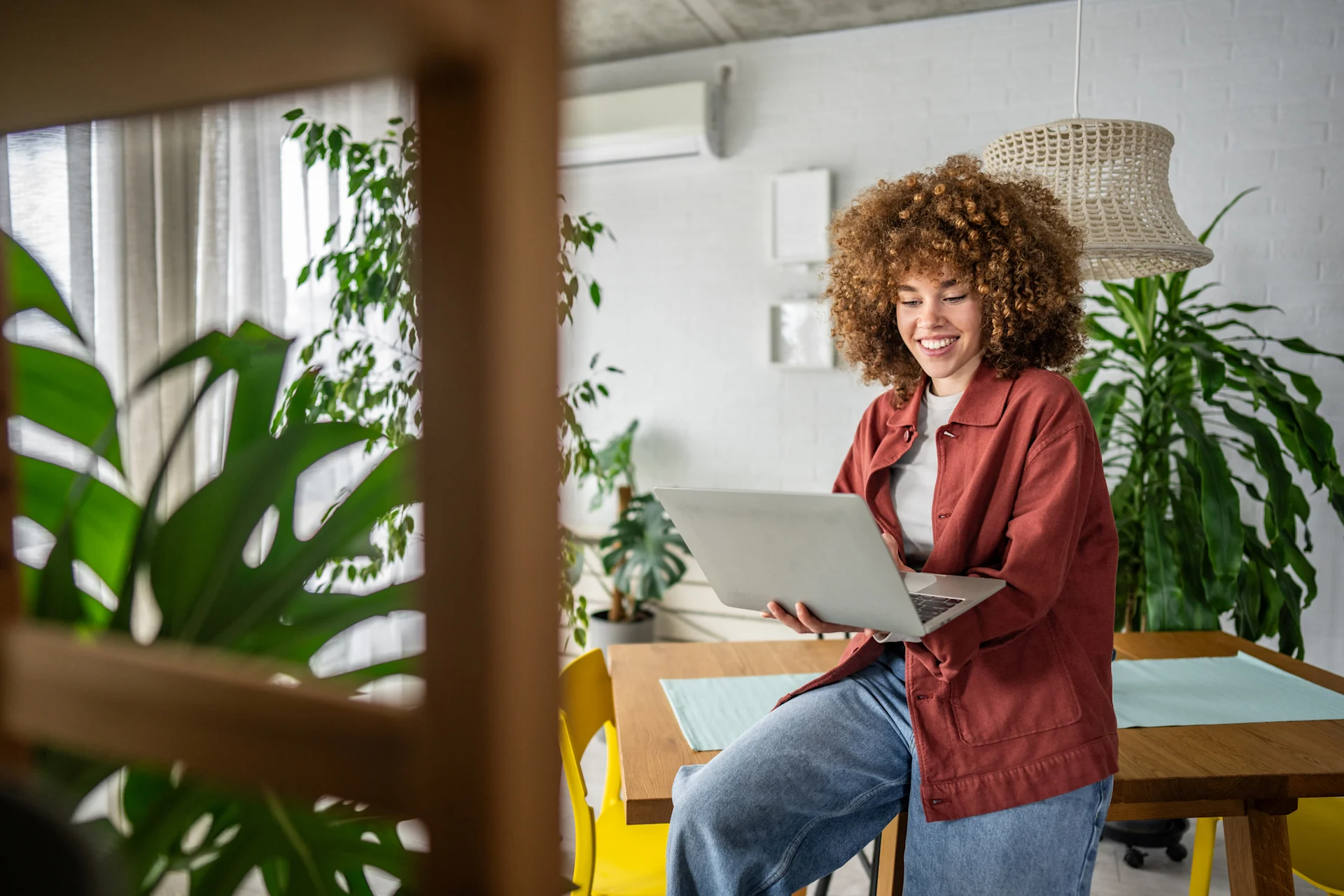 A young female fashion designer with afro hair sketches her ideas while working on her laptop. This scene blends traditional artistry with modern technology, showcasing her creativity and dedication to the fashion industry.