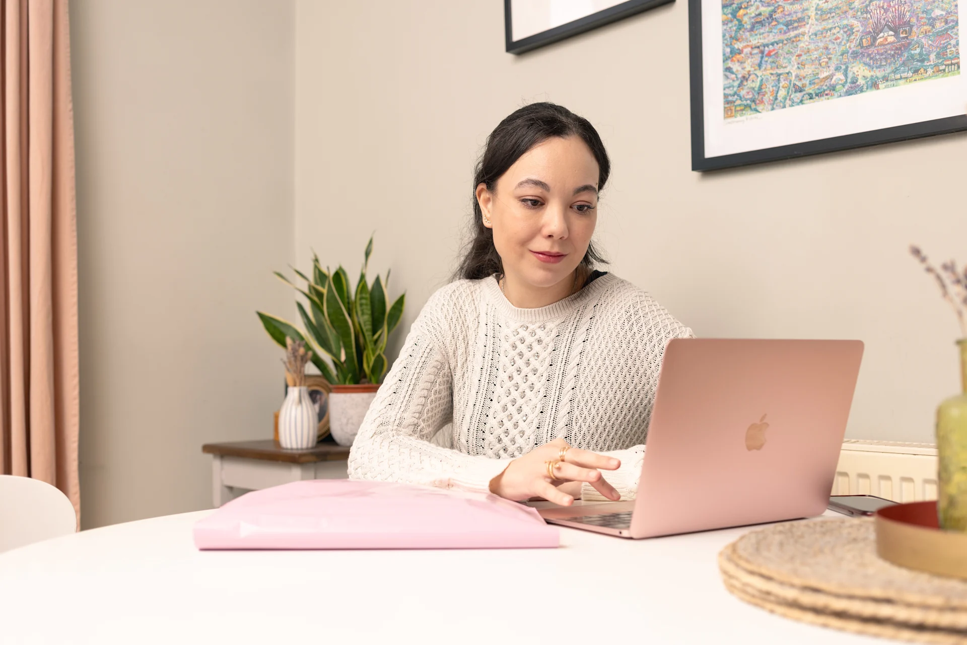 Woman checking her pink laptop.