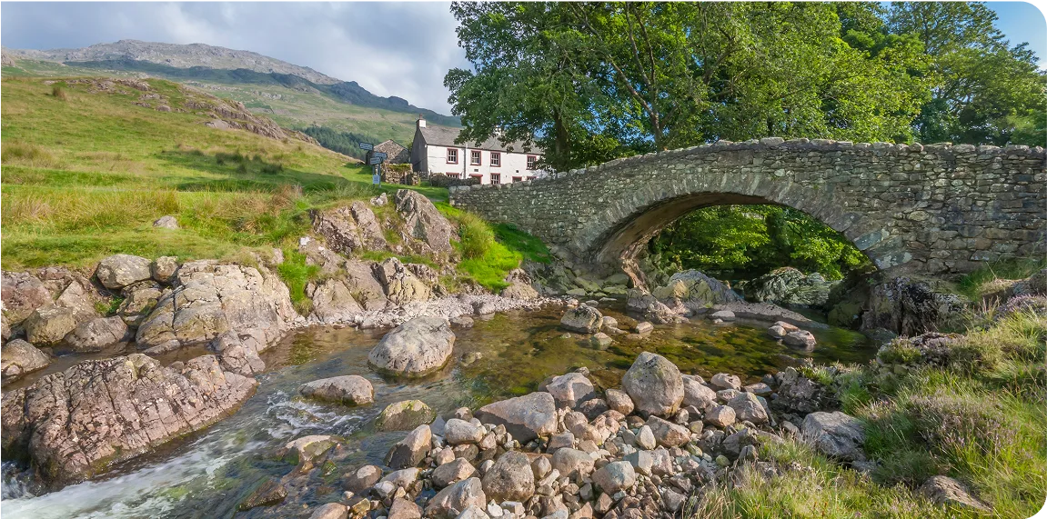 Scenic view of a house across a stream and a bridge.